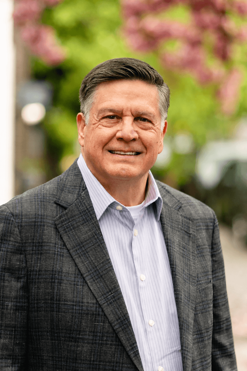 Mark Norman, smiling, photographed outdoors with cherry blossoms in the background.